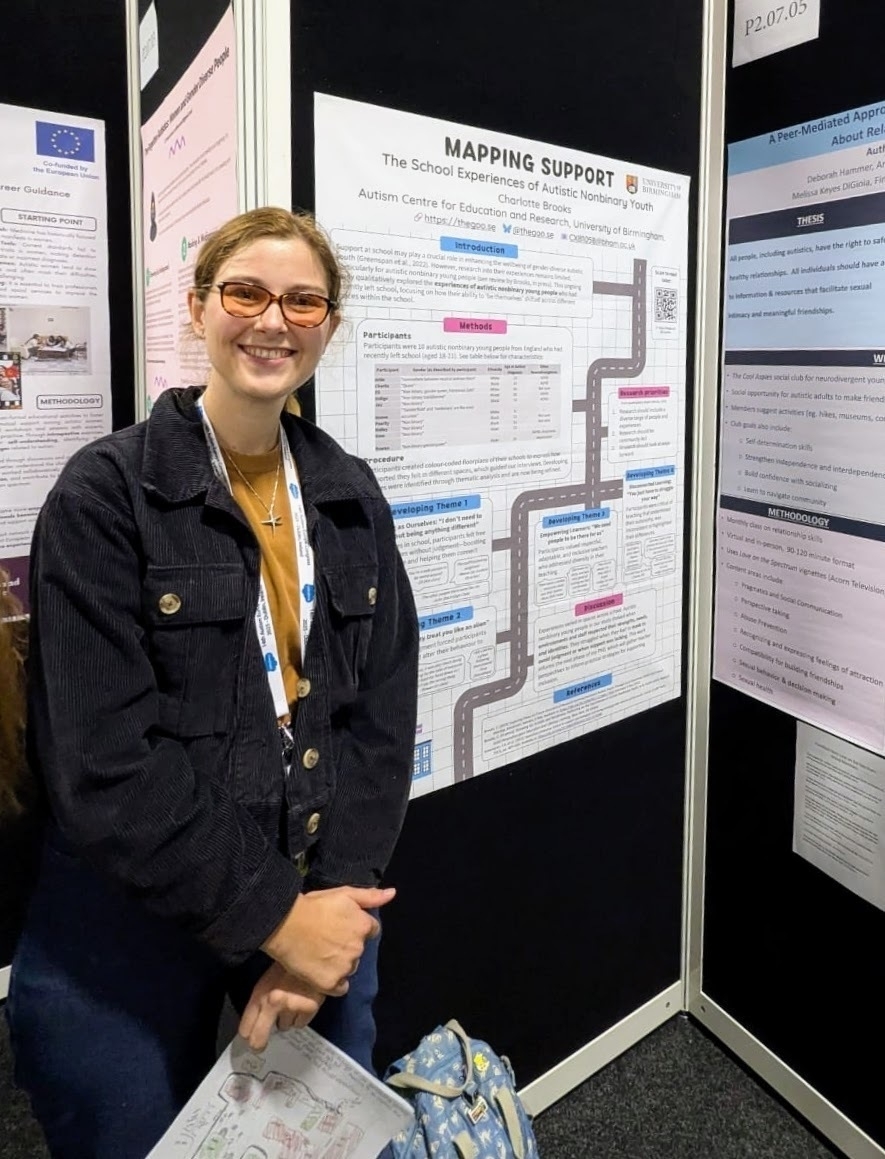 Charlotte stands smiling in front of a poster titled "Mapping Support" at the Autism Europe 2025 conference.